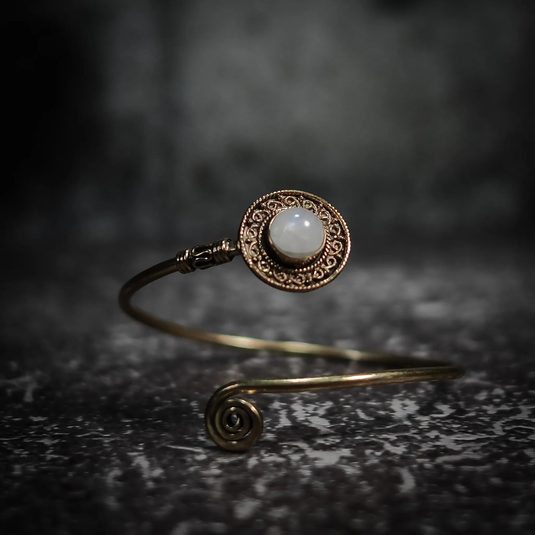 Justerbart armband med ljus-grå labradorit, dekorativ mässing­behållare och filigrerad ornamentik.