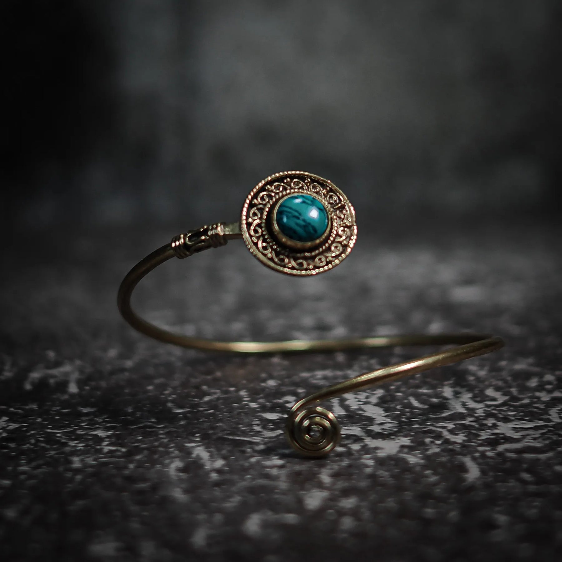 Justerbar sköld-armband med labradorit visar­lande teal-blå glans, dekorativ mässing och antikt filigrerad ornamen­tik.