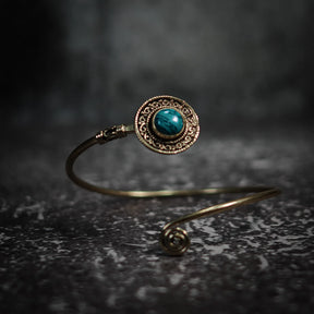 Justerbar sköld-armband med labradorit visar­lande teal-blå glans, dekorativ mässing och antikt filigrerad ornamen­tik.