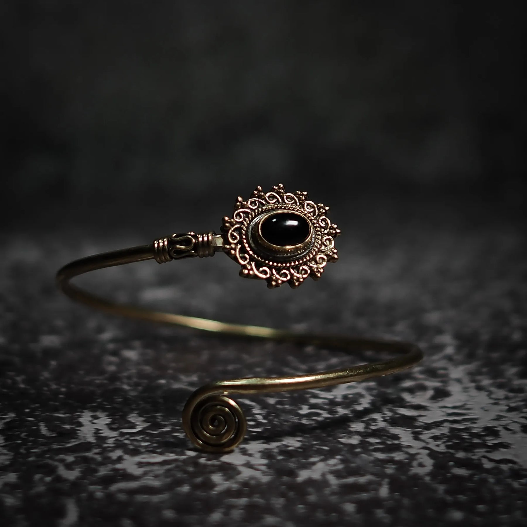 Vikingarmband i svart halvädelsten med ornamenterad filigre design och spiralformad terminal