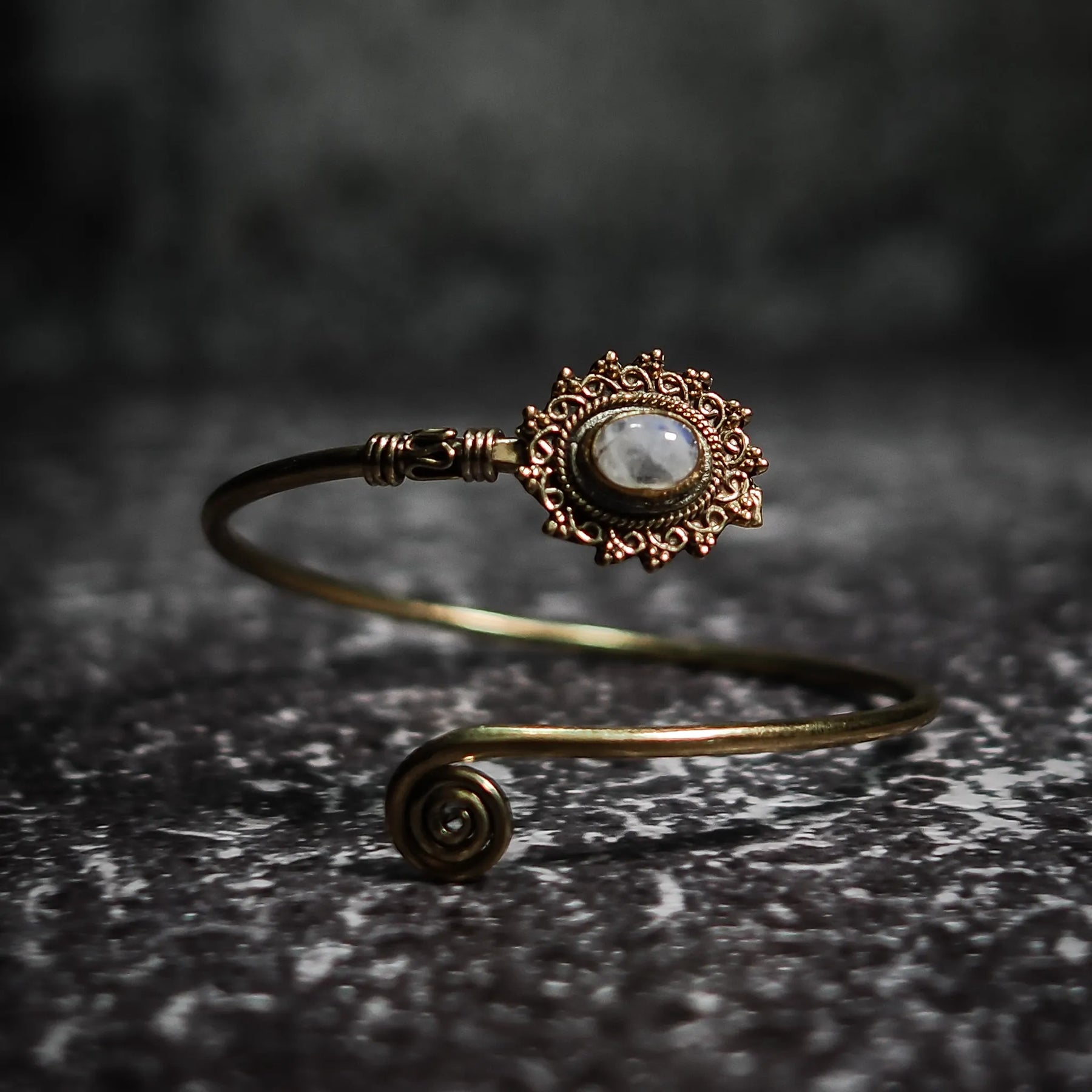 Vikingarmband i vit/grå halvädelsten med ornamenterad filigre och spiralformad terminal på texterad bakgrund