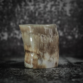 Whiskyglas i naturlig horn med synlig spräckled mönster och organisk textur, minimalistisk presentation