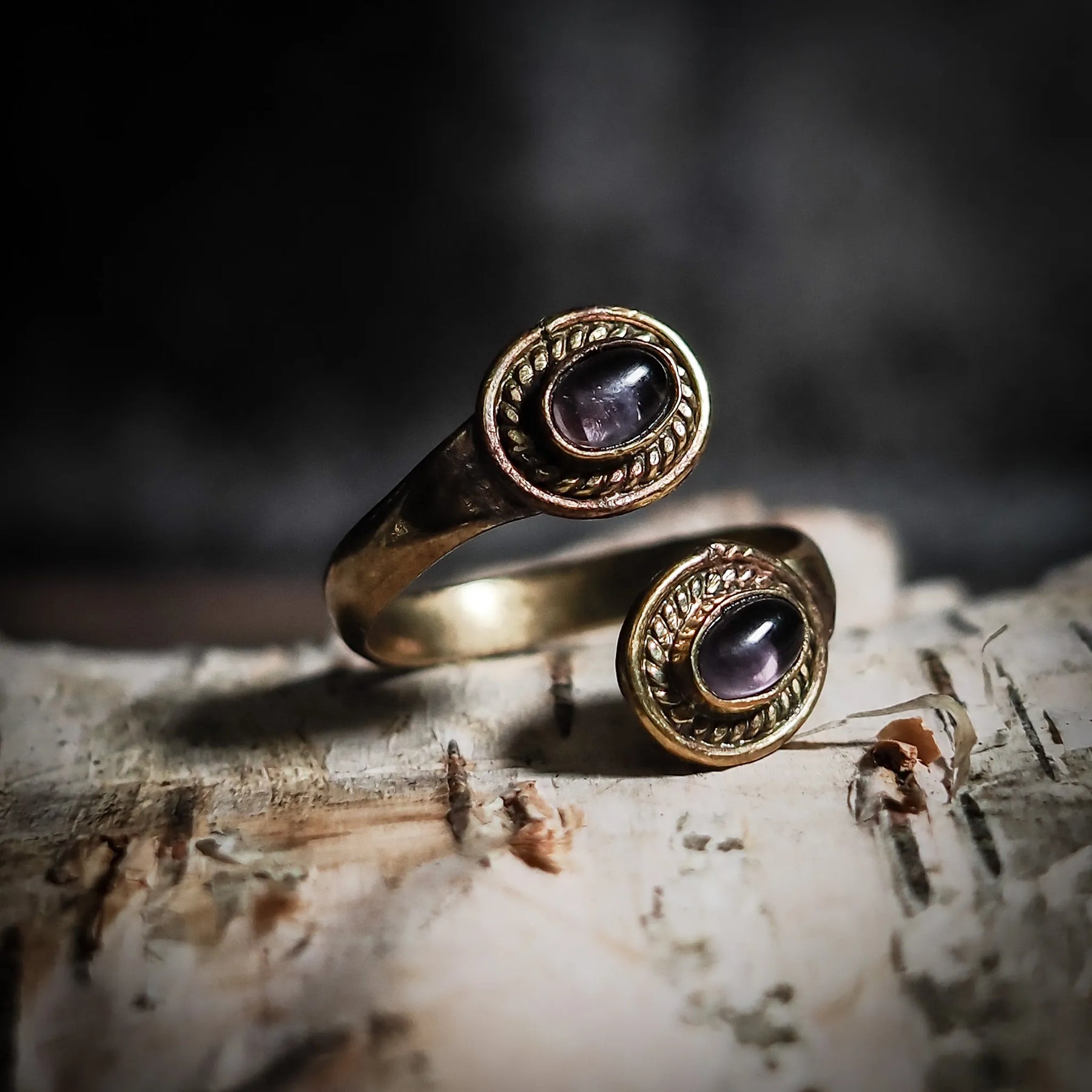 Spiralring i mässing med två ljusa labradoriter med månsteensglöd, på trä