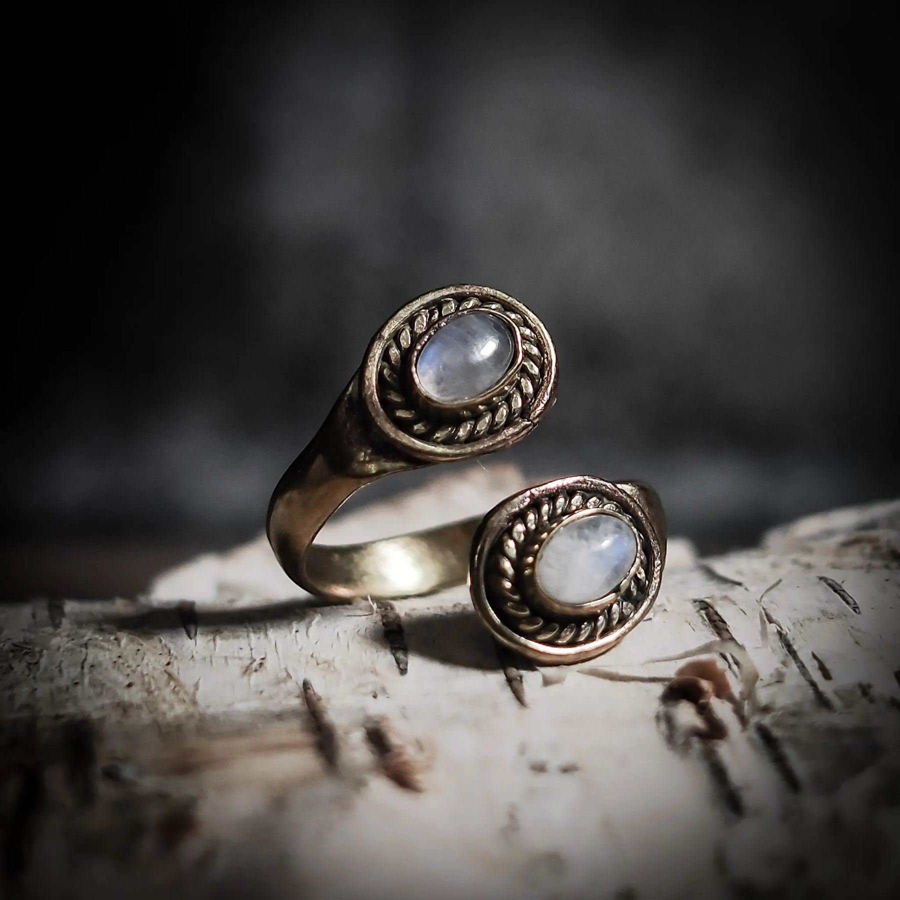 Spiralring i mässing med två svarta labradoriter i snirklade fasetter, på trä