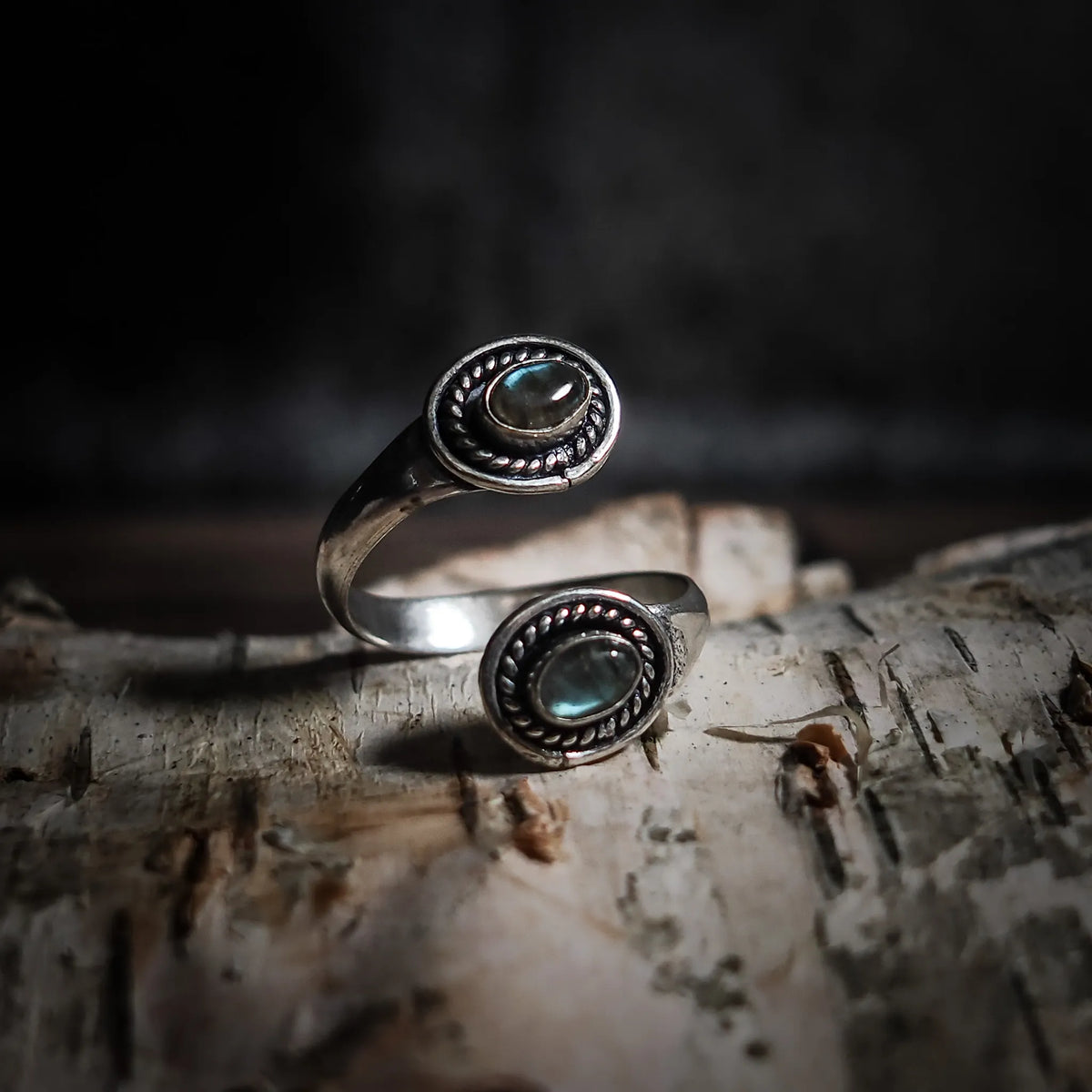 Spiralring med labradorit halvädel som visar norrskenets blå-gröna glimmring, justerbara mässing med dekorativ flätat betoning.