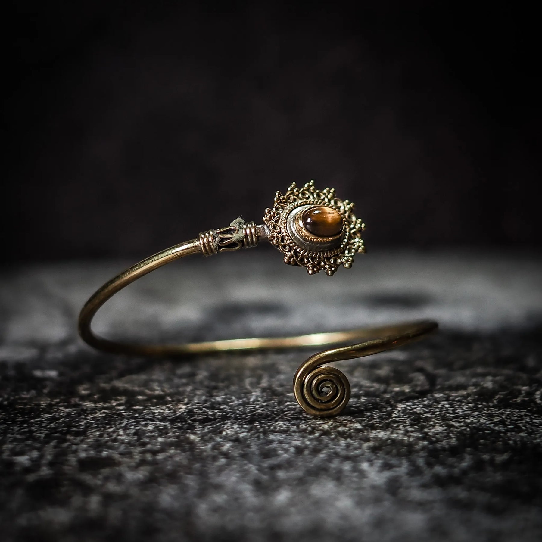 Vikingarmband i gyllene bärnsten med dekorativ filigre innfattning och spiralformad terminal