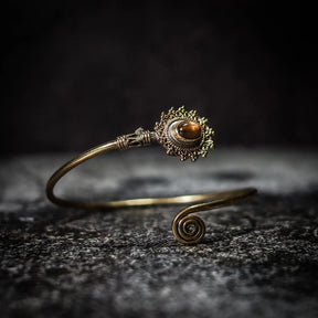 Vikingarmband i gyllene bärnsten med dekorativ filigre innfattning och spiralformad terminal
