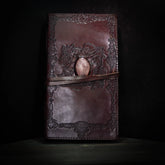 Brunt lädernotisar med vikingmönster och rosenkvarts-kristall på framsidan