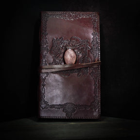 Brunt lädernotisar med vikingmönster och rosenkvarts-kristall på framsidan