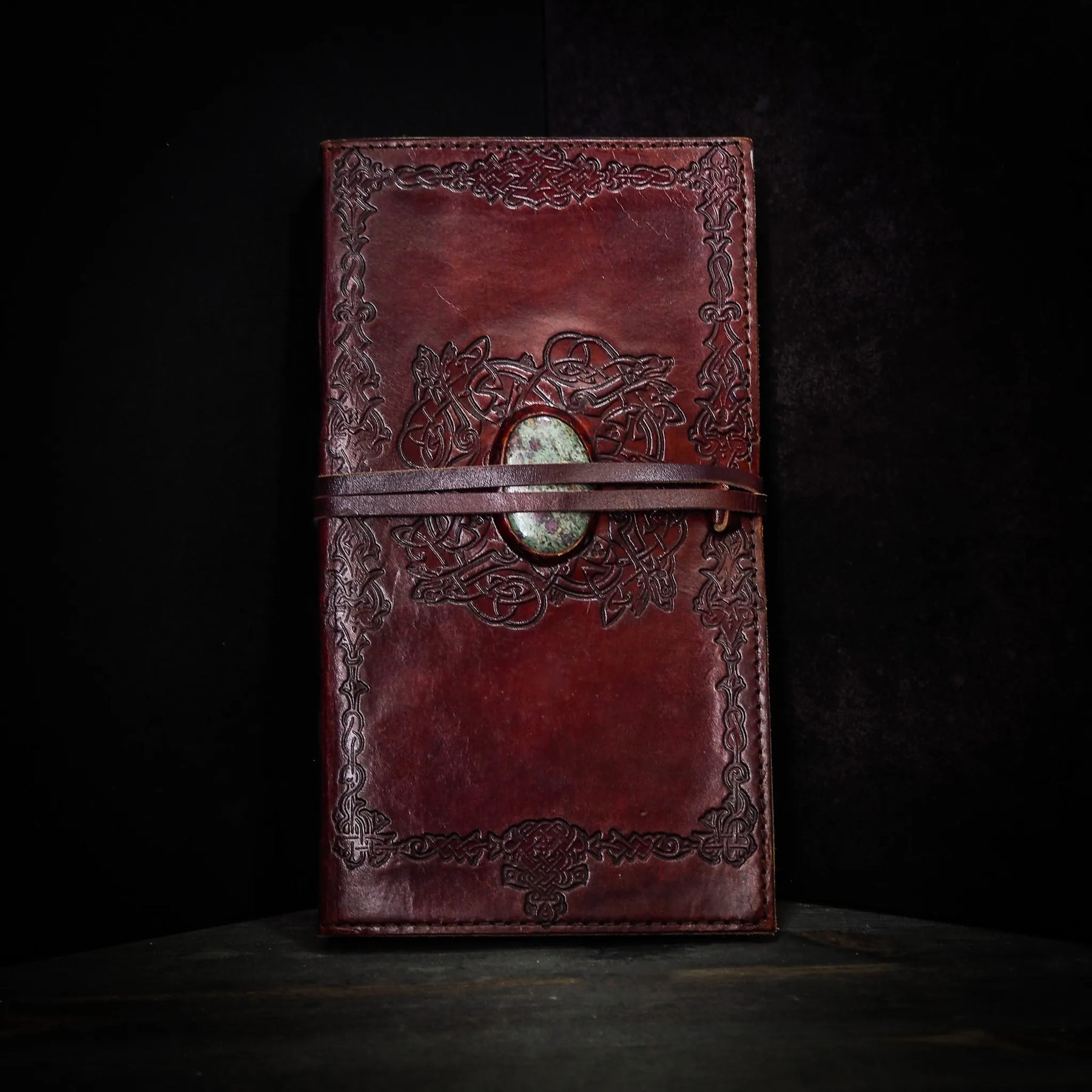 Mörkbrunt lädernotisar med vikingmönster och ljus grön-vit kristall