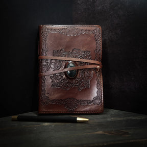 Handgjord läderbok Kristall i medium med moss-agat-sten. Burgundibrunt läder med präglad vikingmönsterkant, grön moss-agat-sten i metallfattning och brunt läderband.