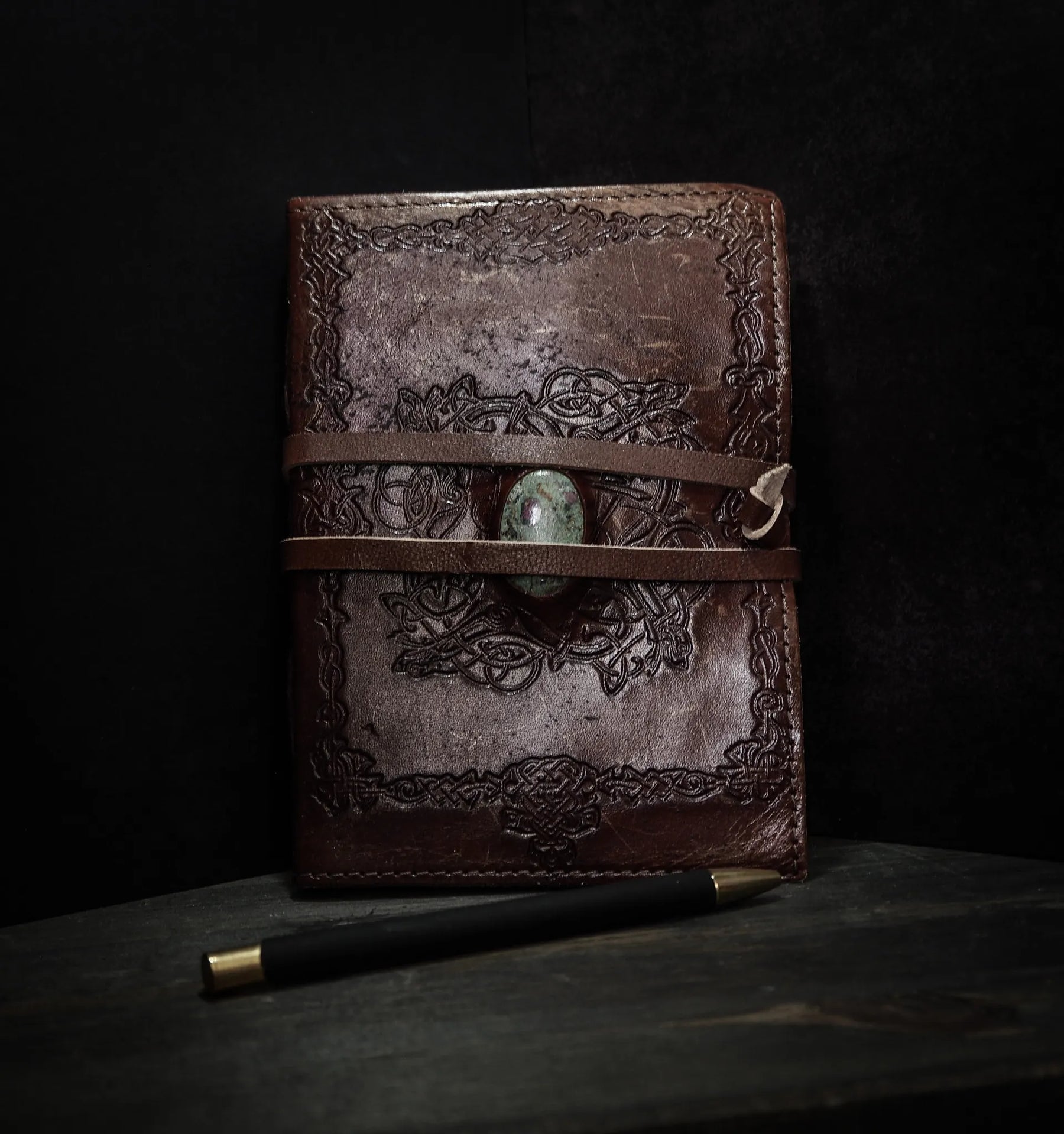 Handgjord läderbok Kristall i medium med moss-agat-sten. Brunt präglat läder med vikingmönster, grön moss-agat-sten i center och två läderband.