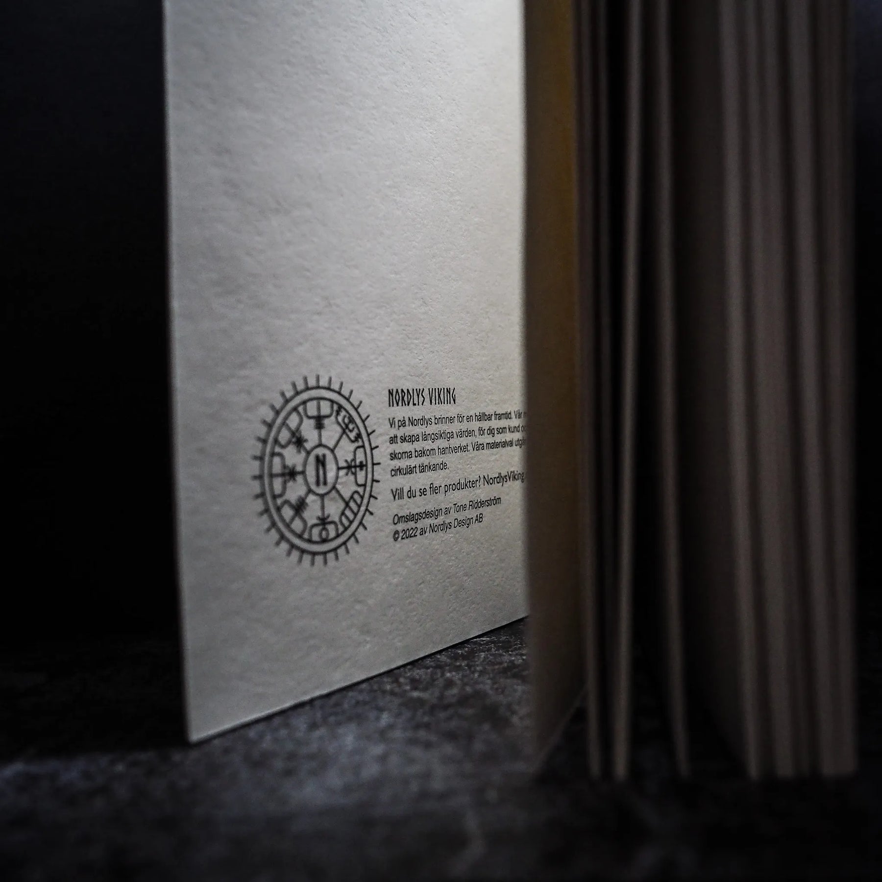 Baksida av målarbok med stor Vegvisir-runskirckel, Nordlys Viking-branding och Swedish produktbeskrivning på handgjord återvunnen papper
