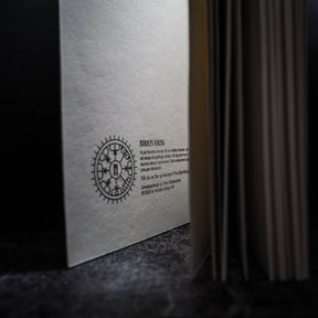 Baksida av målarbok med stor Vegvisir-runskirckel, Nordlys Viking-branding och Swedish produktbeskrivning på handgjord återvunnen papper