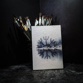 A6 målarbok, Skyddsruna med Aegishjalmur. Omslag visar vintrig skogsbakgrund med barrträd och vattenreflektion. Runmotiv i centrum. Känd som skyddsruna i nordisk tradition.