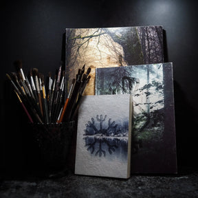 A6 målarbok, Skyddsruna med Aegishjalmur, visad med penslar. Arrangement visar omslag, innehållssida och runmotiv. Konstnärlig presentering.