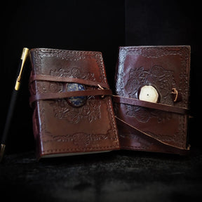 Liten läderbok Kristall öppen, visar brunt skinn med vikingamönster och inlagd Lapis Lazuli-sten på insidan