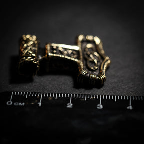 Bronze Thor's hammer pendant shown next to metric ruler for scale, displaying intricate Norse knotwork detail