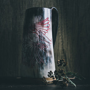 Hornöl mugg med graverad viking design. Två klassiska norska korpar (Hugin och Munin) med utspridna vingar och nordiska runor mellan dem. Naturlig hornfärg, ljus krämfärg. Dekorerad med torkade växter.