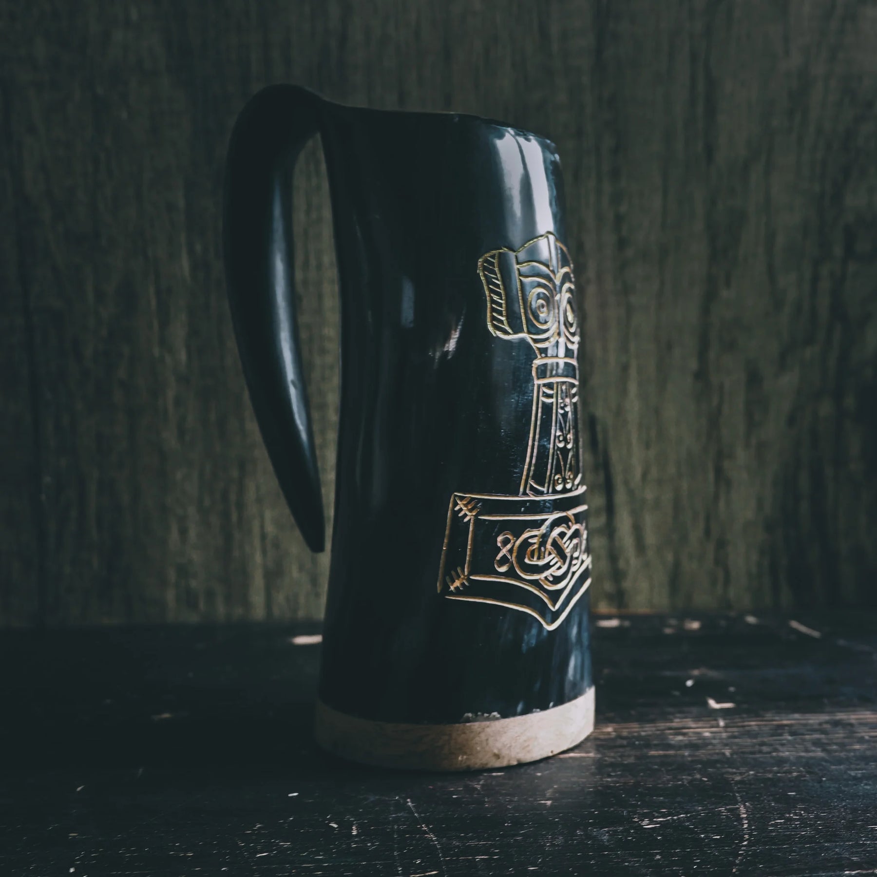 Black polished organic horn beer mug shown in profile with gold-inlaid Thor's hammer and Nordic decorative patterns