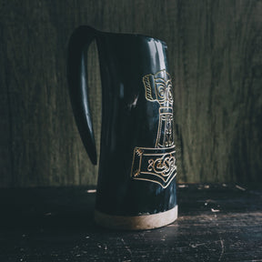 Black polished organic horn beer mug shown in profile with gold-inlaid Thor's hammer and Nordic decorative patterns
