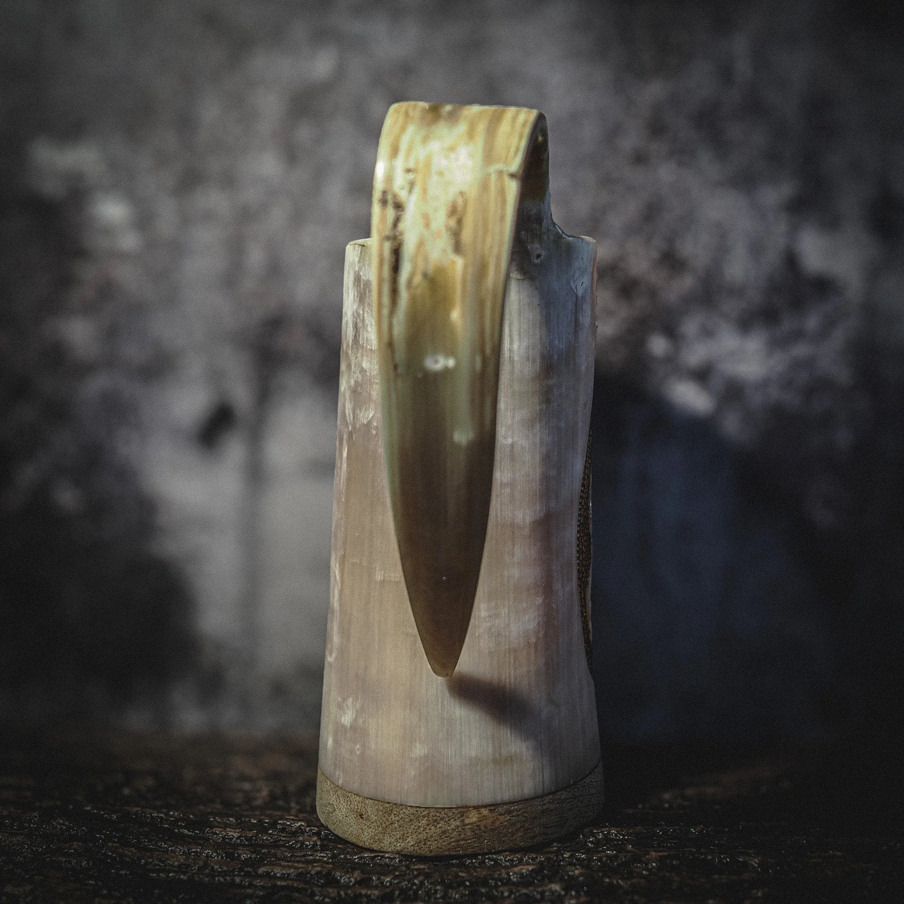 Handsnidad hornmugg i djupskuren design med Urnes drakmotiv och pyrografi, sedd från baksidan. Organic horn i kräm- och mörkbrun färg med naturlig patina mot mörk bakgrund.