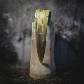 Handsnidad hornmugg i djupskuren design med Urnes drakmotiv och pyrografi, sedd från baksidan. Organic horn i kräm- och mörkbrun färg med naturlig patina mot mörk bakgrund.