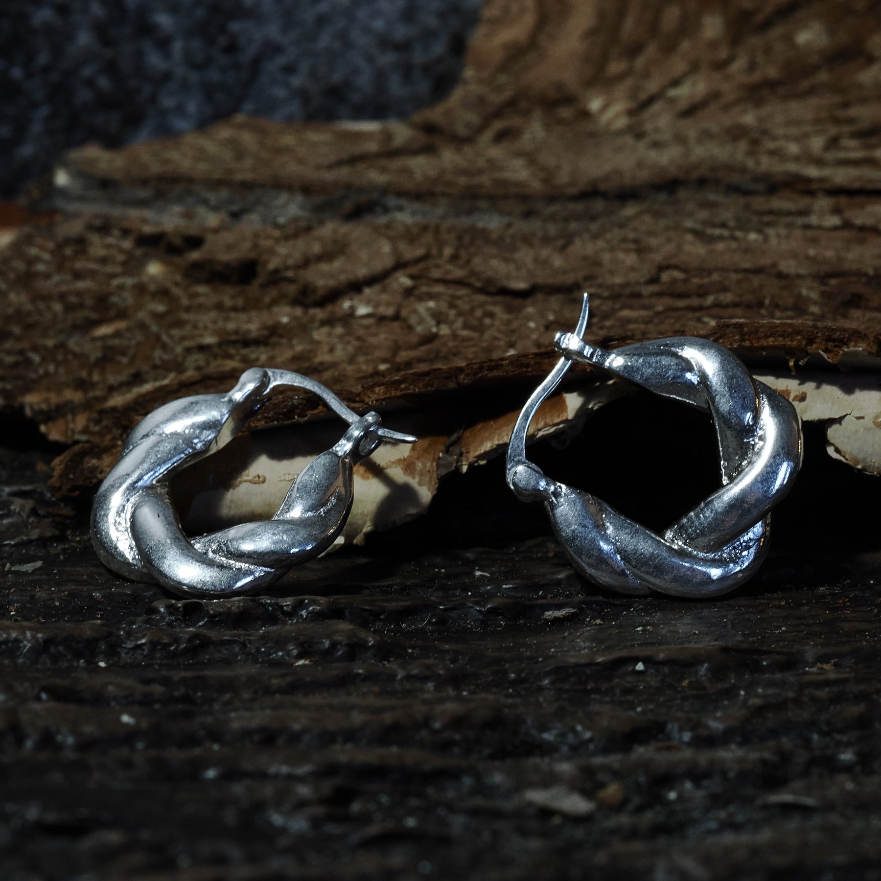 Par örhängen i silveröverlagring flätad mässing på mörk träbas, cirka 2 cm stora