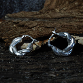 Par örhängen i silveröverlagring flätad mässing på mörk träbas, cirka 2 cm stora