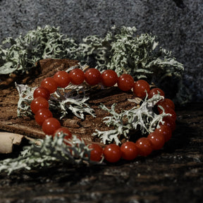 Armband stenpärlor - Tigeröga variant med karneol. Elastiskt armband med röda polerade karneol-pärlor på rustik träbas med mossbeväxt stenbackgrund.