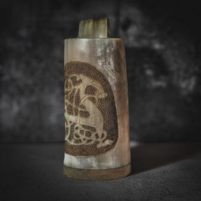 Handsnidad hornmugg i frontvy med djupskuren Urnes-drake och pyrografi-mönster. Organic horn i naturliga kräm- och bruntonanger, sett mot neutral bakgrund.