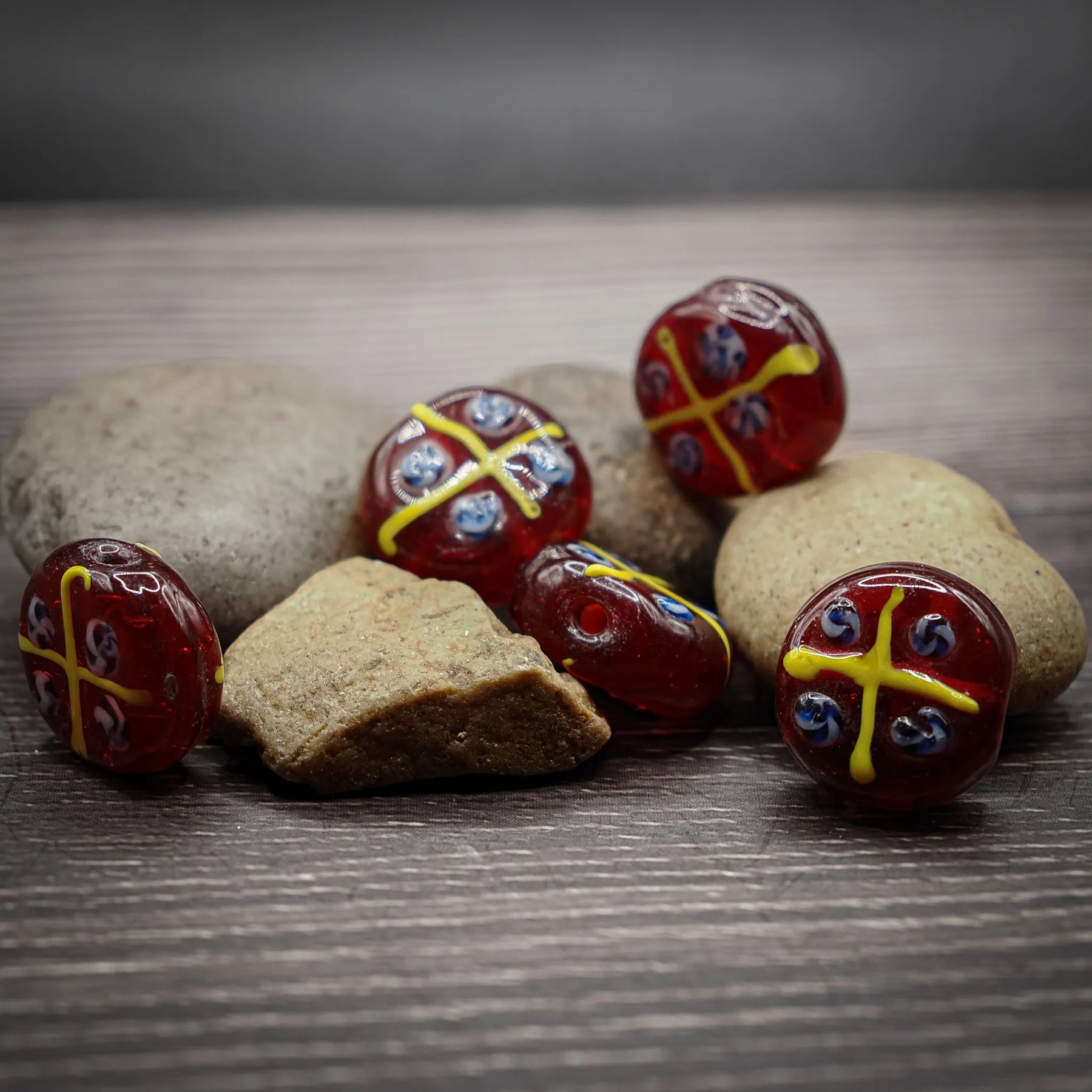 Red glass bead with yellow and blue decorative pattern, glossy finish, approximately 15-20mm diameter, intricate Viking-inspired design