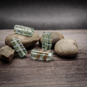 Mintgrön glaspärla med metallisk dekordetalj, cirka 22mm rektangulär form, på naturlig stenbakgrund