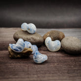 Vit och blå glaspärla från Ragnarök-serien. Fem pärlor visar den unika hopvikta geometriska strukturen med blå virvlar inuti transparent vitt glas. Varje pärla är cirka 15 mm.