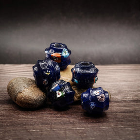 Mörkblå stor glaspärla samma som IMG_9241. Facetterad form med färgglad emaljdekor i olika vinklar. Visar pärlornas geometri och emalytystruktur. 17x16mm med 5mm hål.