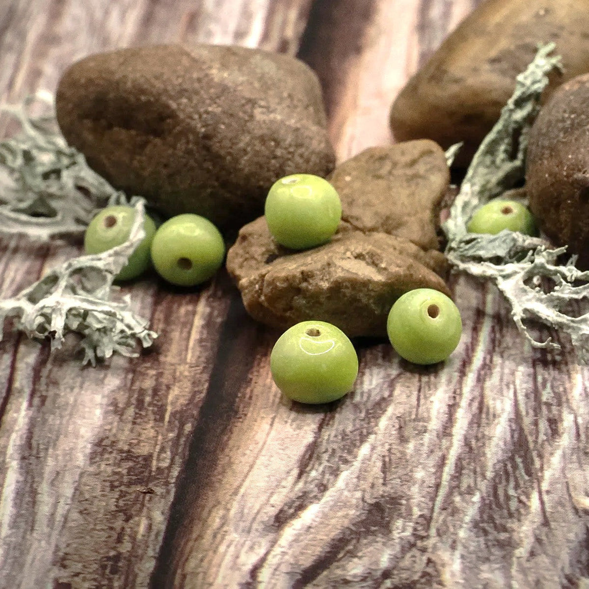 Fem ljusgula glaspärlor på rustikt trä med moss, naturlig styling, ca 7mm diameter