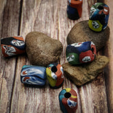 Flerfärgad cylindrisk glaspärla med målad Ragnarök-motiv. Pärlan visar detaljerade ansikten i rött, orange, blått, gult och vitt på 17x12mm med 4mm hål för trådning.