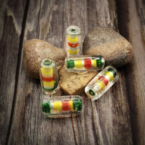 Transparenta tubformade glaspärlor med färgade kärnor på trä