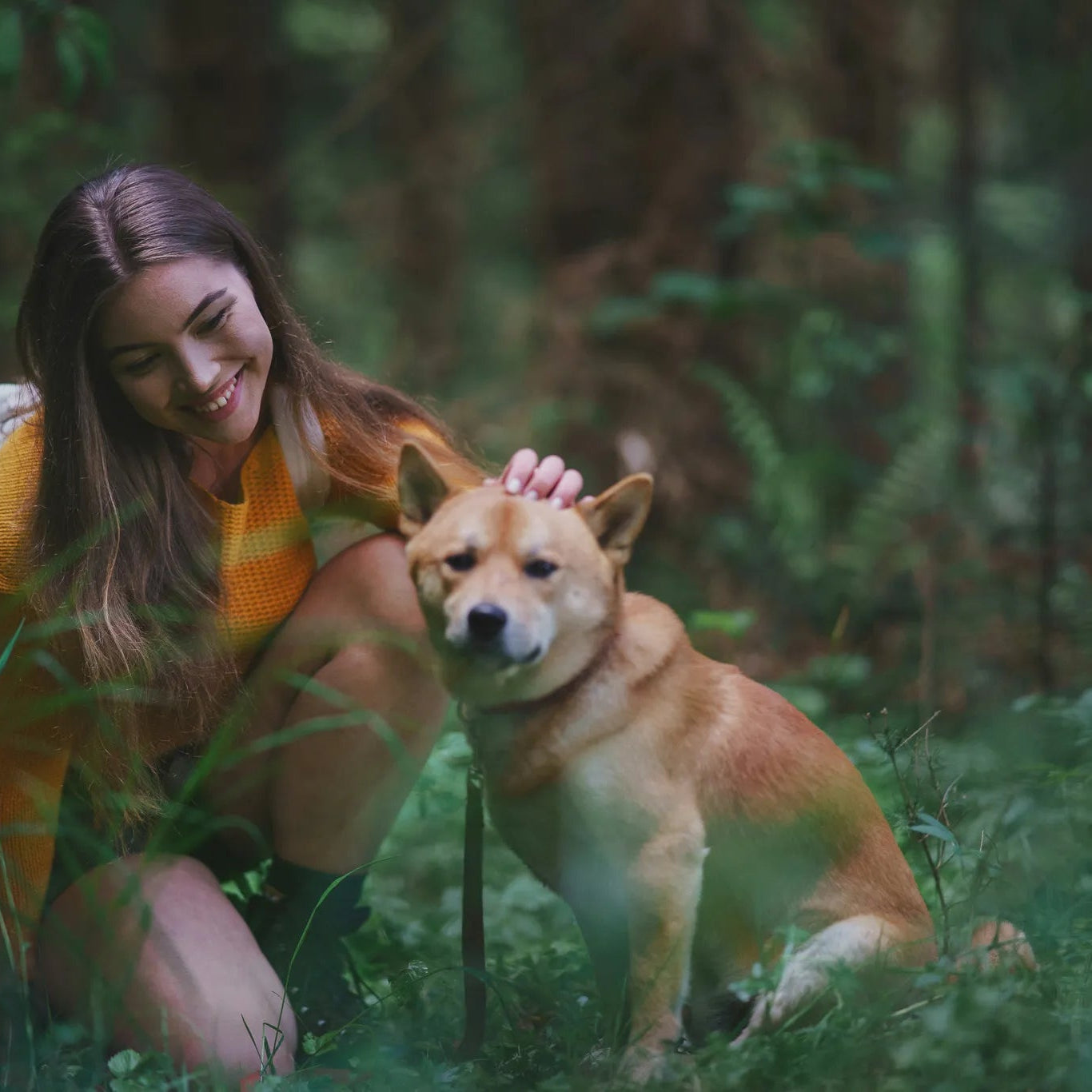 Livsstilsbild av kvinna i gul utomhuskläder med brun hund i skogsmiljö. Titeln 'Kalla på hunden' visar visselpipans praktiska användning som hundsignal under vandring och outdoor-aktiviteter.