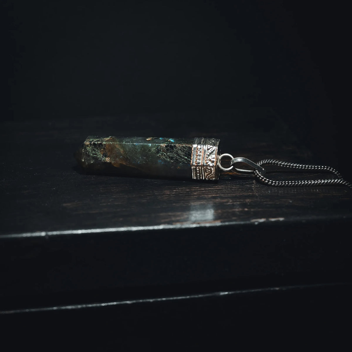 Labradorit-hänge med iriserade blå-gröna ljusblixtar. Polerad kristallsten med metallfattning och ögonkrok. Kedja säljs separat. Studio-produktfoto på vit bakgrund.