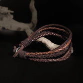 Flettet og enkelt læderarmbånd i lysere og mørkere brunt læder med metalbeslag. Vikingeinspireret armbånd med naturlig patina og justerbart design.