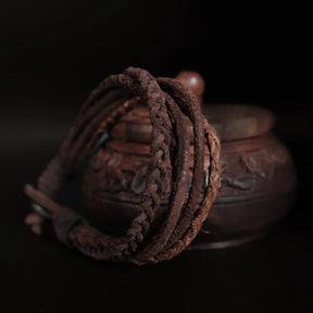 Läderarmband i brunt med flera flätade läderband, uppspänd för att visa konstruktion och längd