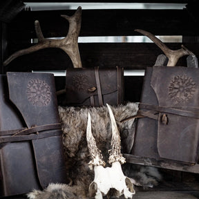 Three leather notebooks with Vegvisir symbols arranged with faux fur prop, Nordic Viking lifestyle photography with dark background