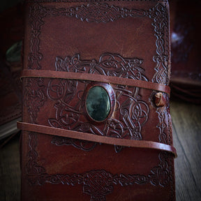 Handgjord läderbok Kristall i medium med moss-agat-sten. Brunt präglat läder med vikingmönster, pale grön moss-agat-sten med dendritiska mönster och brunt läderband.