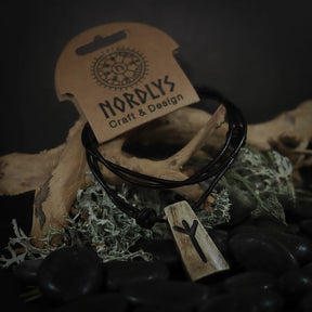 Runhalsband i handgjort oxben på svart lädersnöre. Rununsymbolen är inristad i det naturliga, ljusa benets. Produkten är presenterad på rustik bakgrund med mossa och naturliga element för att framhäva dess nordiska ursprung.