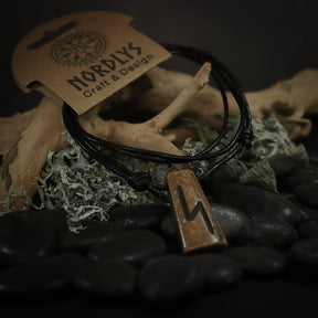 Handgjord runhalsband i oxben med svart lädersnöre. Runitskriften är tydligt inristad i det ljusa benets. Produkten är styladpå naturlig bakgrund för att framhäva dess autentiska, nordiska karaktär.