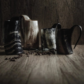 Kaffekrus i horn – fire krus i forskellige nuancer og mønstre stillet op ved kaffebønner