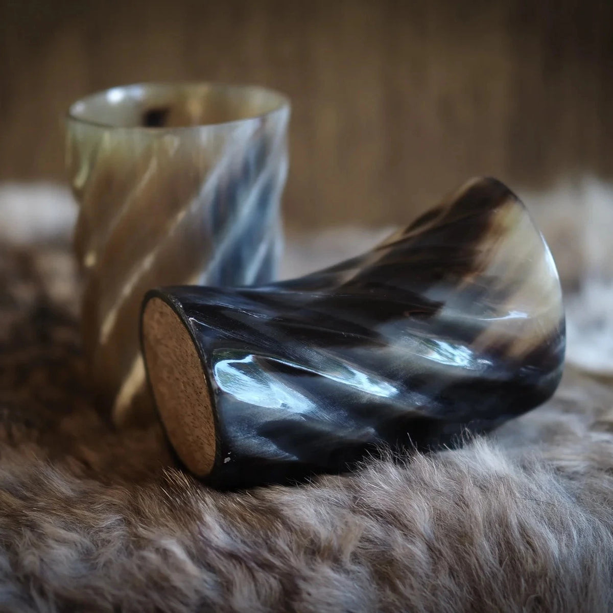 Handsnidad whiskyglas av horn med spiraldesign, mörkhorn med naturlig yta, på träbas