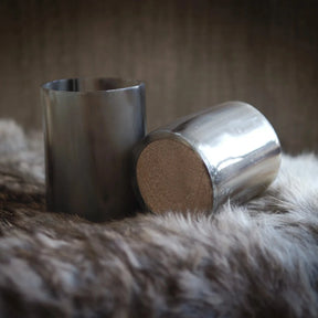 Två hornglasögon för whisky fotograferade tillsammans, visar träbotten och polerad kant mot neutral textilbakgrund.