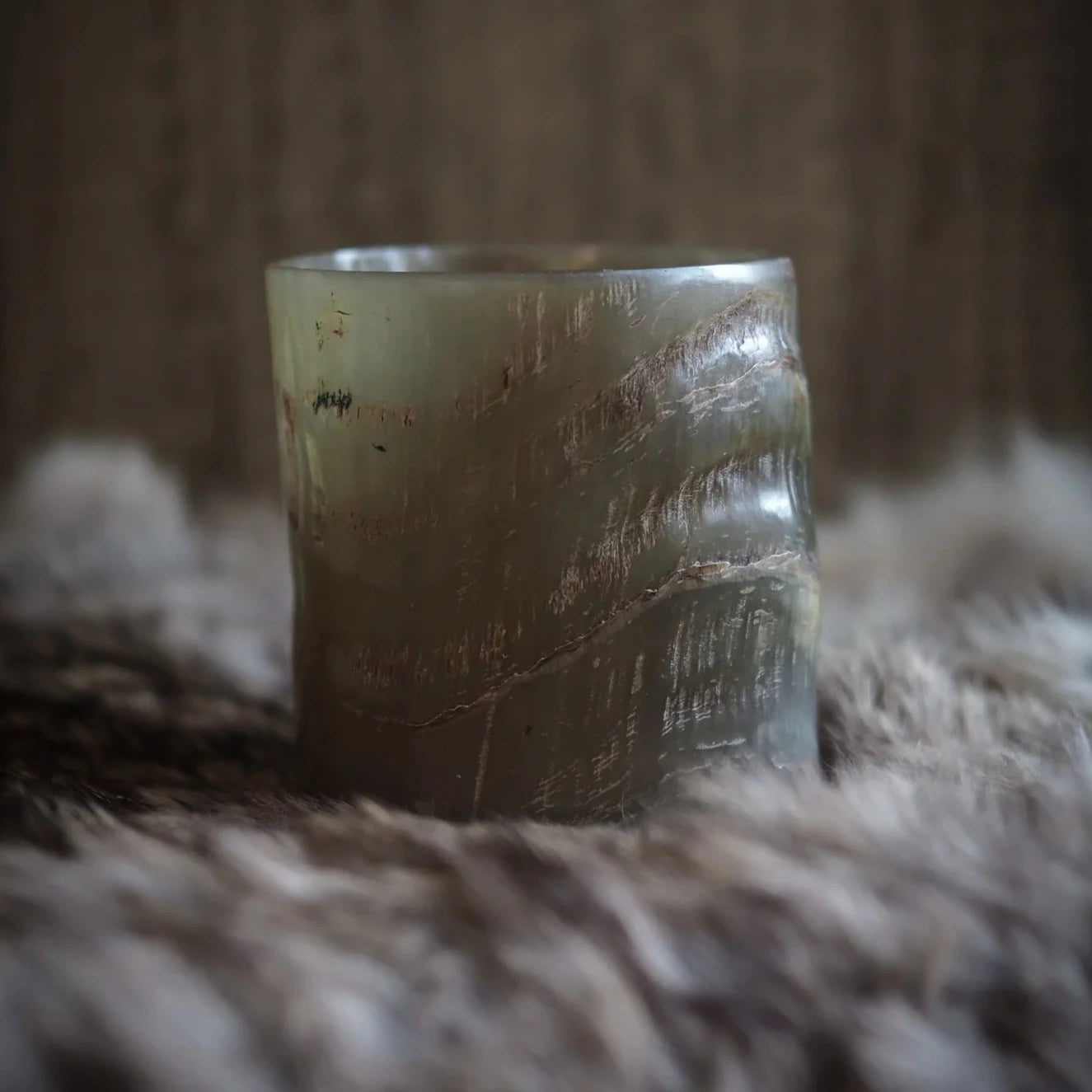 Hornglasögon för whisky fotograferad från sidan, visar transparent naturlig färg och organiska randiga mönster mot neutral bakgrund.